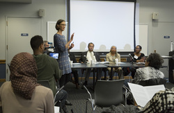 Photograph of Ansley Erickson (standing) greeting participants at Modern School multigenerational reunion